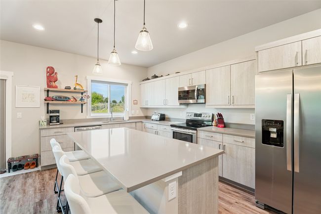 Kitchen with appliances with stainless steel finishes, a sink, a breakfast bar area, light countertops, and recessed lighting | Image 13