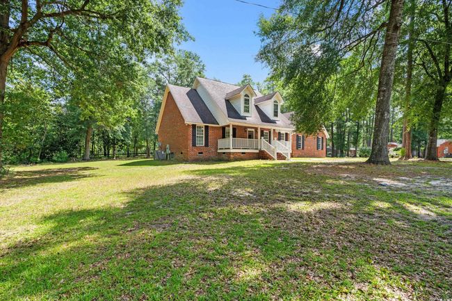 Rear view of house with crawl space, brick siding, a lawn, and covered porch | Image 10