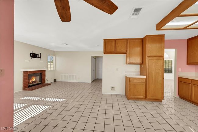 Unfurnished living room with a ceiling fan, visible vents, a fireplace, and light tile patterned floors | Image 15