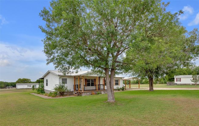 Manufactured / mobile home featuring covered porch, a front yard, a metal roof, and a detached carport | Image 6