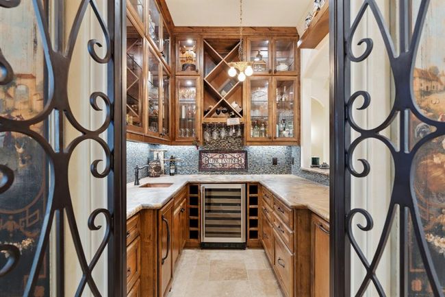 Beautiful 8' tall arched-top iron gates open into the custom-designed full bar, perfect for wine storage or mixing the latest and greatestcocktails and beverages. | Image 7