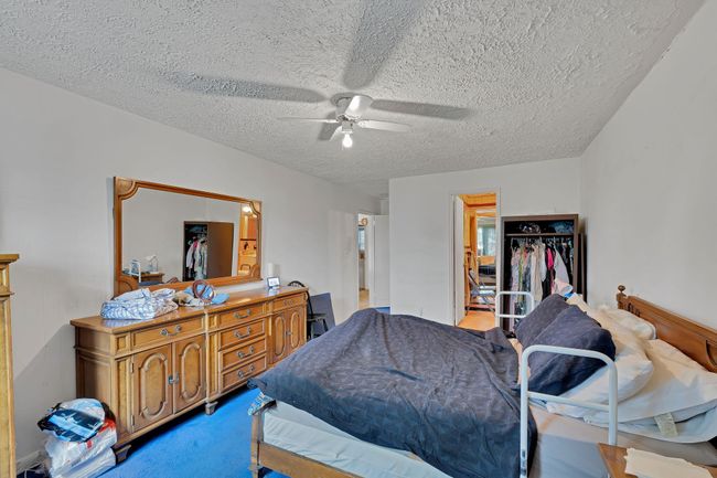 Bedroom featuring a spacious closet, a textured ceiling, ceiling fan, and carpet floors | Image 6