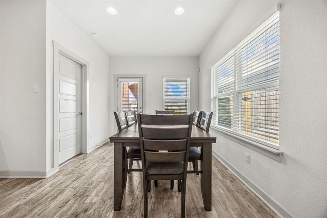 Another angle of the dining area, highlighting the large windows that fill the space with natural light and the sleek vinyl flooring that runs throughout the home. | Image 10