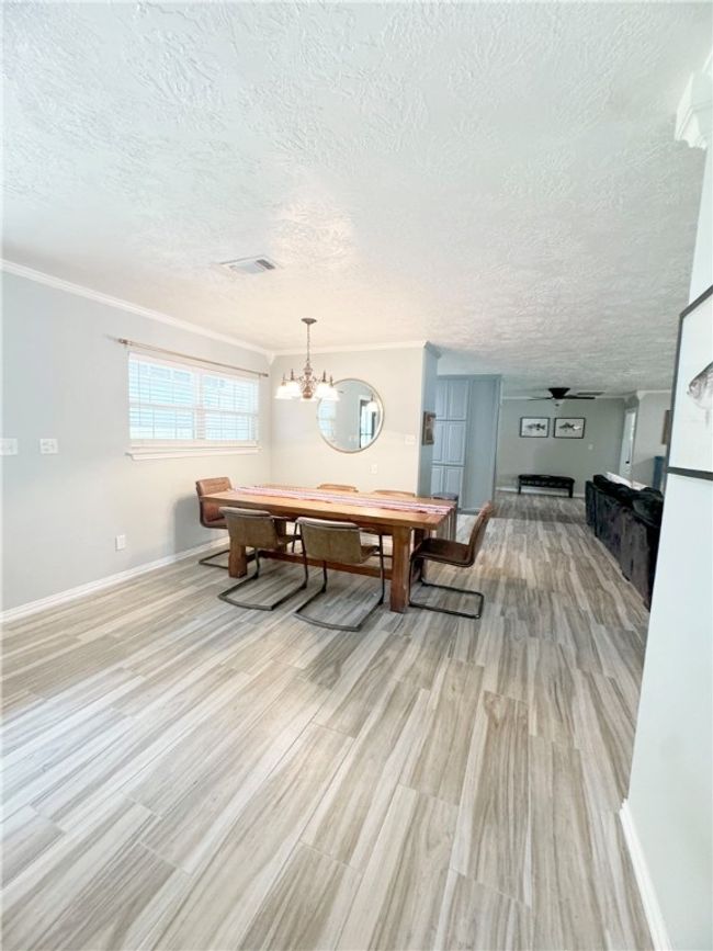 Dining area featuring crown molding, a textured ceiling, light wood-style flooring, a notable chandelier, and visible vents | Image 16