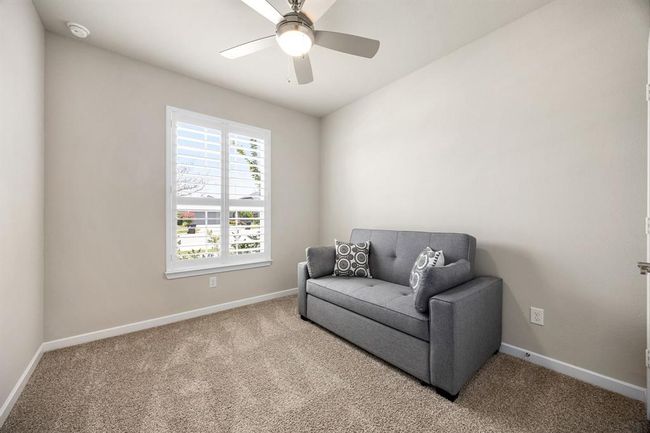 Secondary Bedroom that faces the front of the home. Plantation shutters and ceiling fan keeps this space cool and private for your guests. | Image 24