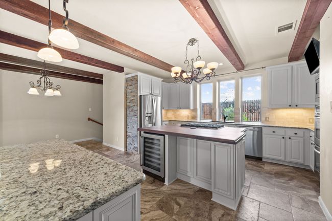 Kitchen with wine cooler, appliances with stainless steel finishes, a chandelier, butcher block counters, and decorative backsplash | Image 8