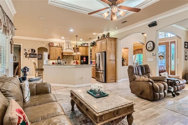 Living area featuring visible vents, light wood-type flooring, ornamental molding, arched walkways, and ceiling fan | Image 7