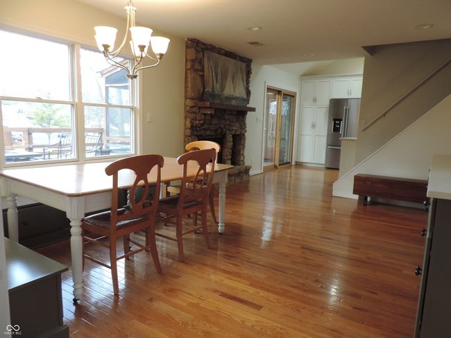 dining room featuring stairs, a notable chandelier, a fireplace, and light wood finished floors | Image 11