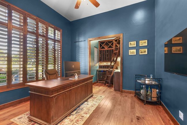 Home office with light wood-style floors, ceiling fan, and wine cooler | Image 6