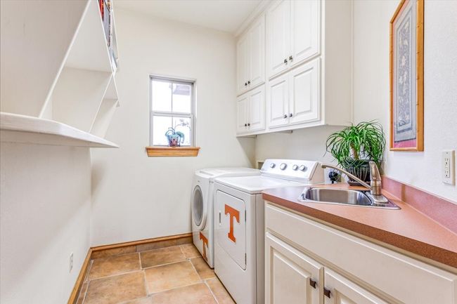 Washroom featuring washer and clothes dryer, baseboards, cabinet space, and light tile patterned floors | Image 27