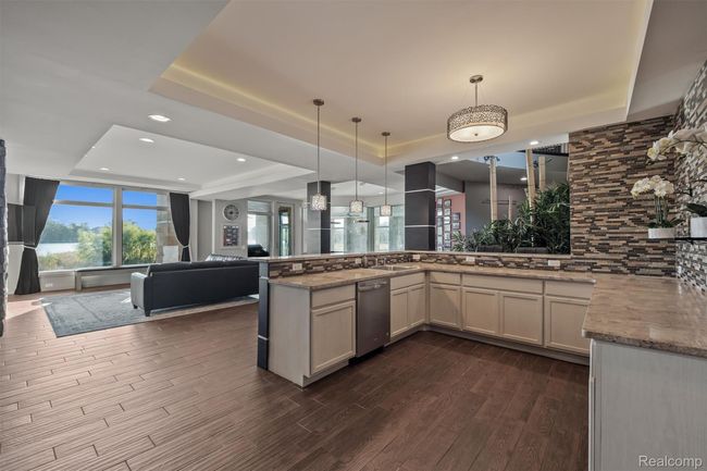 Kitchen featuring a tray ceiling, open floor plan, tasteful backsplash, decorative light fixtures, and recessed lighting | Image 52