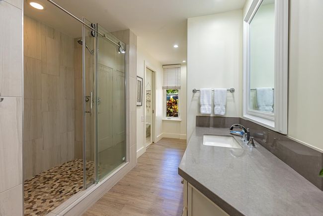 The primary bathroom features Silestone quartz countertops & a walk-in shower with custom details | Image 17