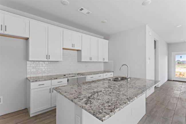 Kitchen featuring sink, white cabinetry, tasteful backsplash, and light hardwood / wood-style flooring | Image 7
