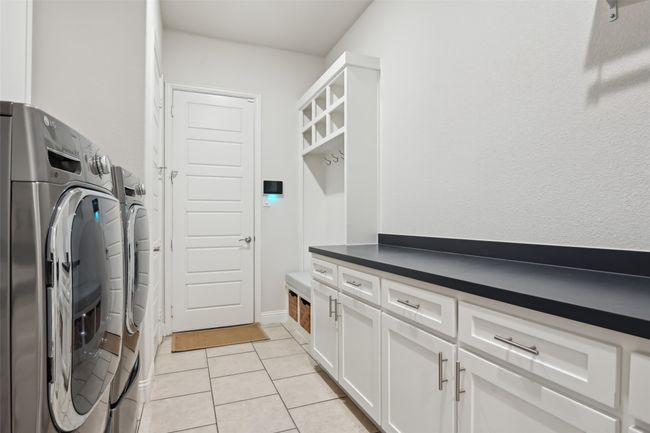Laundry area featuring washing machine and clothes dryer, light tile patterned floors, and cabinet space | Image 26