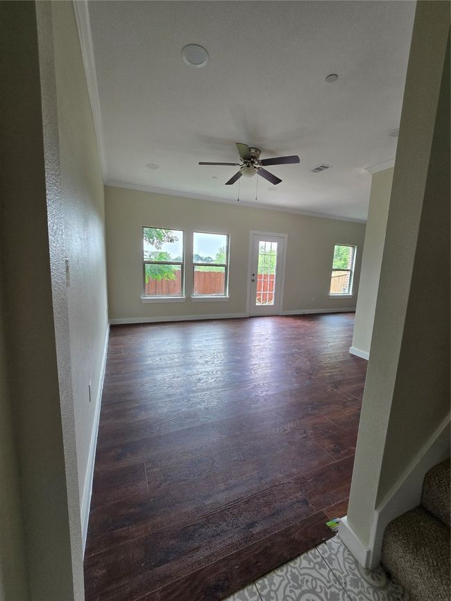 Unfurnished room featuring ornamental molding, a ceiling fan, dark wood-style floors, baseboards, and stairway | Image 4