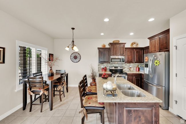 Kitchen with stainless steel appliances, light tile patterned flooring, recessed lighting, backsplash, and dark brown cabinetry | Image 7