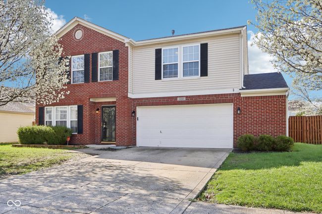 traditional home with brick siding, driveway, and an attached garage | Image 5