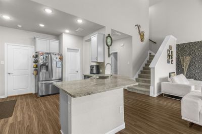 with dark wood-type flooring, sink, white cabinetry, and stainless steel fridge | Image 3