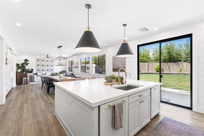 Kitchen with a sink, light wood-type flooring, open floor plan, visible vents, and light countertops | Image 16