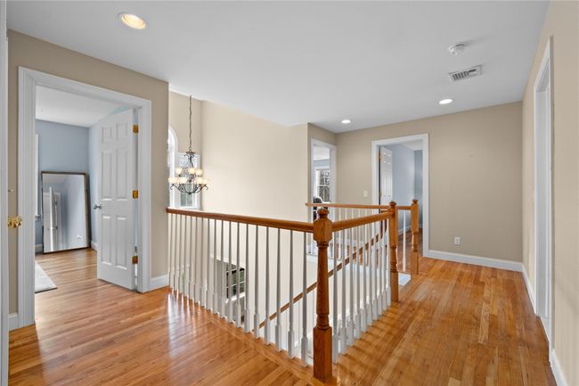 Hall with an inviting chandelier, visible vents, an upstairs landing, light wood finished floors, and baseboards | Image 16
