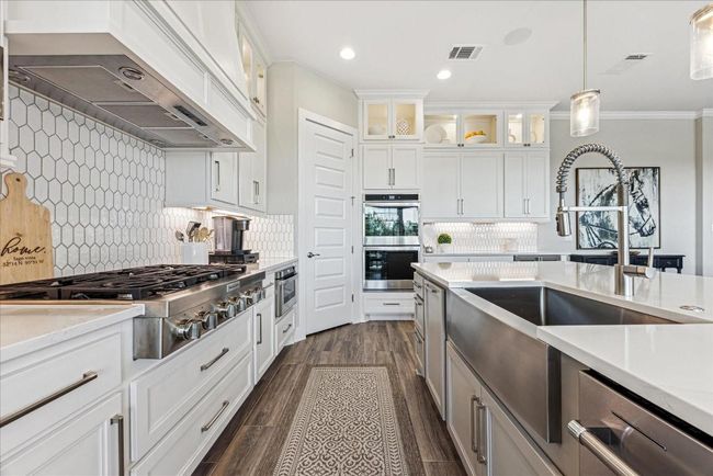 Top-of-the-line stainless steel appliances, including double ovens, a microwave drawer, an upgraded 36" gas cooktop, and a dishwasher, complete the package. A stainless steel farmhouse sink is another fabulous feature that adds both style and functionality to the​​‌​​​​‌​​‌‌​‌‌​​​‌‌​​‌‌​‌​​​​​‌ kitchen. | Image 10
