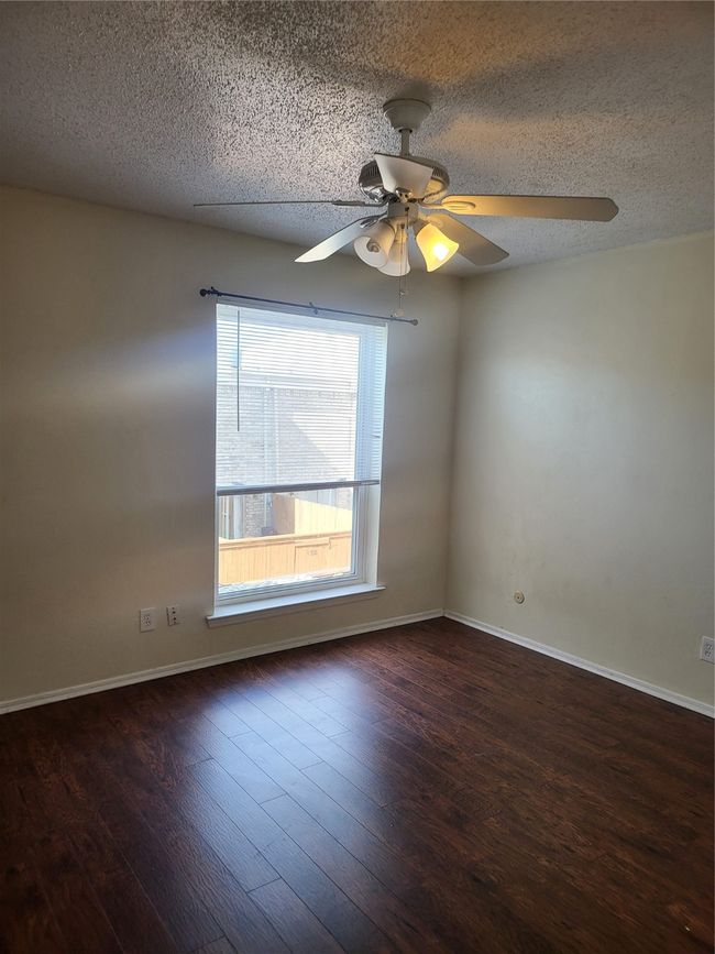 Empty room with baseboards, wood finished floors, a textured ceiling, and ceiling fan | Image 15