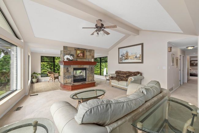 Carpeted living room featuring visible vents, baseboards, a fireplace, and a healthy amount of sunlight | Image 11
