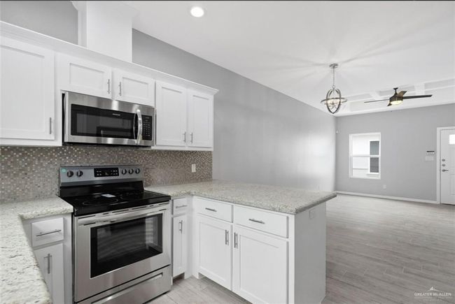 Kitchen with stainless steel appliances, a peninsula, tasteful backsplash, white cabinetry, and recessed lighting | Image 4