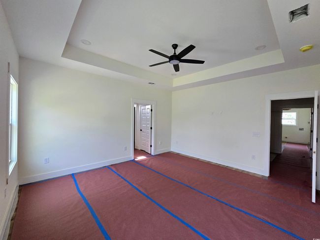 Empty room featuring a raised ceiling, a ceiling fan, and baseboards | Image 21