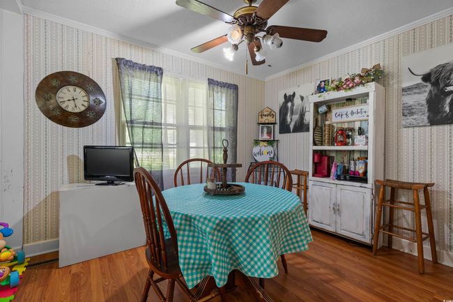 Dining space with wallpapered walls, ornamental molding, wood finished floors, and a ceiling fan | Image 13