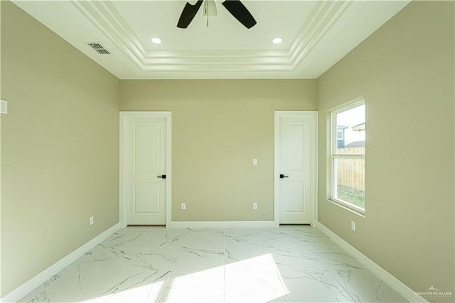 Empty room with marble finish floor, baseboards, visible vents, and a tray ceiling | Image 24