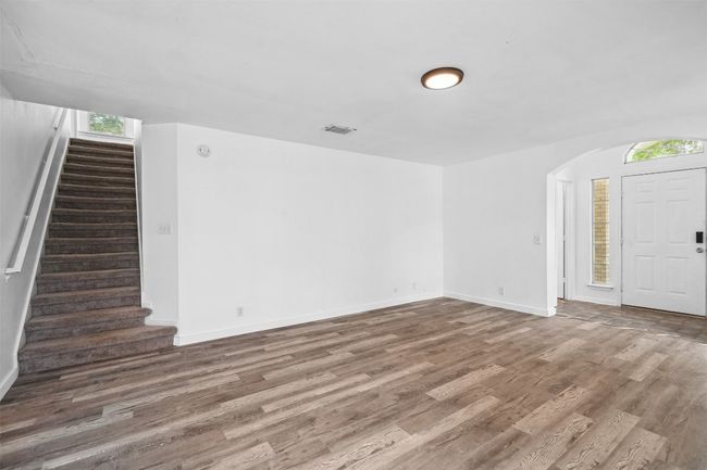 Unfurnished living room with stairway, baseboards, wood finished floors, and visible vents | Image 9