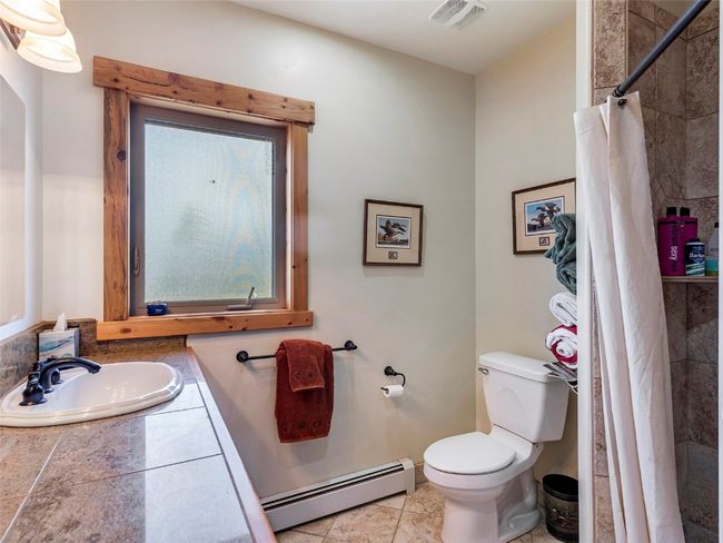 Bathroom with tile patterned flooring, a baseboard heating unit, toilet, and sink | Image 29