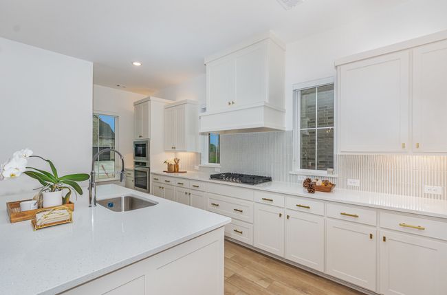 Kitchen featuring appliances with stainless steel finishes, white cabinetry, tasteful backsplash, light wood-style floors, and recessed lighting | Image 5