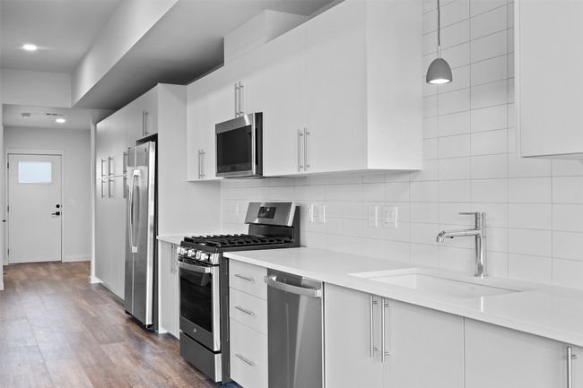 Kitchen featuring appliances with stainless steel finishes, a sink, tasteful backsplash, light countertops, and recessed lighting | Image 6