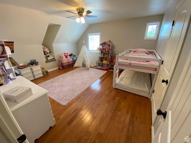 Bedroom with hardwood / wood-style floors, vaulted ceiling, ceiling fan, and baseboards | Image 23
