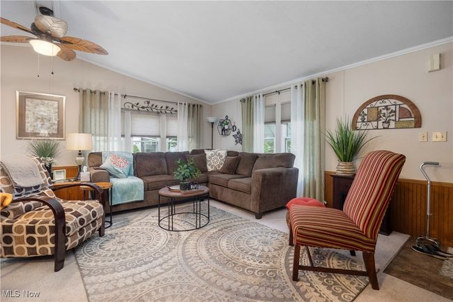 Living room featuring a ceiling fan, crown molding, vaulted ceiling, a wainscoted wall, and wooden walls | Image 18
