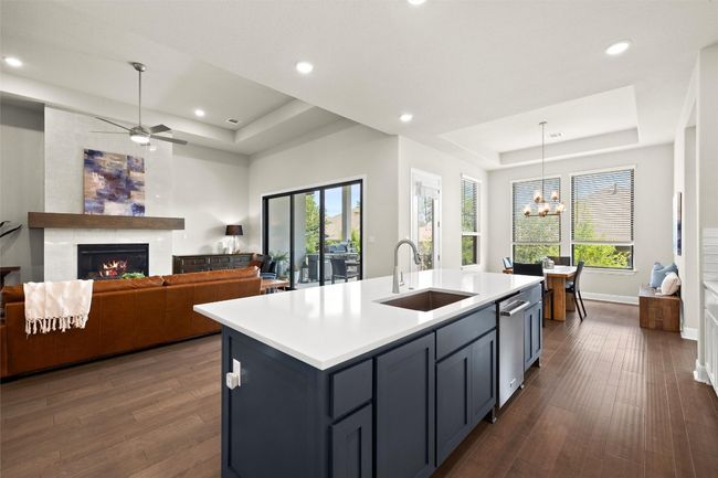 Kitchen featuring a raised ceiling, a tile fireplace, recessed lighting, light countertops, and dark wood finished floors | Image 19