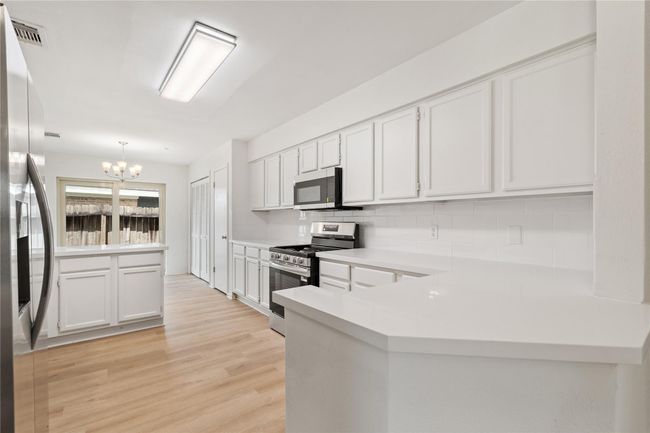 Bright kitchen with white cabinetry, stainless appliances, and functional U-shaped layout. | Image 10