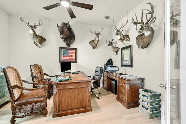 Office area featuring light wood-type flooring, a ceiling fan, and visible vents | Image 9
