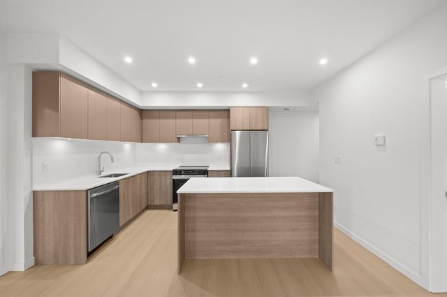 Kitchen featuring appliances with stainless steel finishes, modern cabinets, a kitchen island, light wood-style flooring, and recessed lighting | Image 5