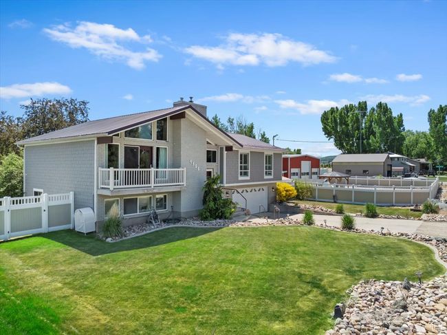 Back of property with an attached garage, a chimney, metal roof, and driveway | Image 34
