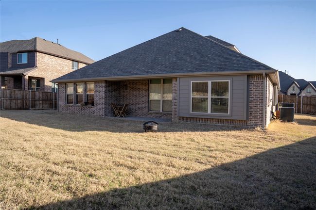 Back of property with brick siding, a lawn, a fenced backyard, and central AC unit | Image 25
