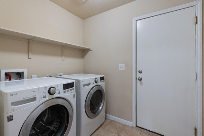 The laundry is found in a separate room with shelf space above. | Image 24