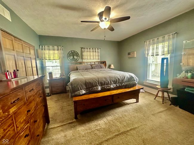 bedroom featuring light carpet, a textured ceiling, multiple windows, and a ceiling fan | Image 27