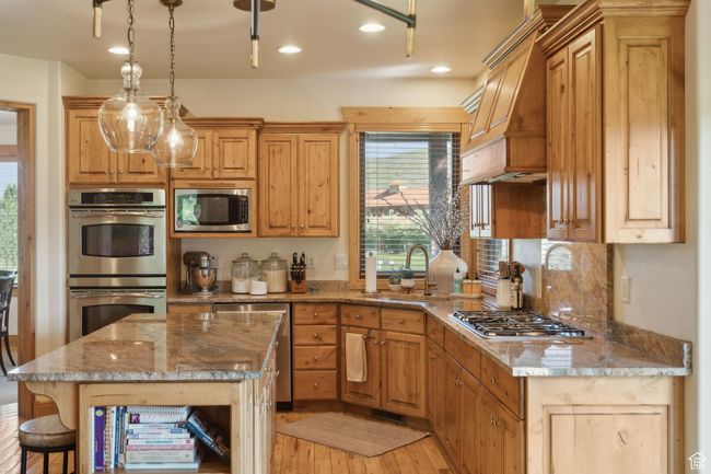 Kitchen featuring appliances with stainless steel finishes, a sink, light wood finished floors, custom exhaust hood, and recessed lighting | Image 6
