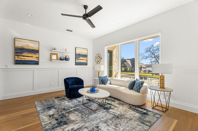 Living area with wood-type flooring, a ceiling fan, a decorative wall, and visible vents | Image 20