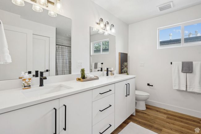 Bathroom featuring baseboards, wood finished floors, visible vents, and a sink | Image 25