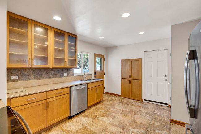 Kitchen with tasteful backsplash, stainless steel appliances, light countertops, and a sink | Image 6