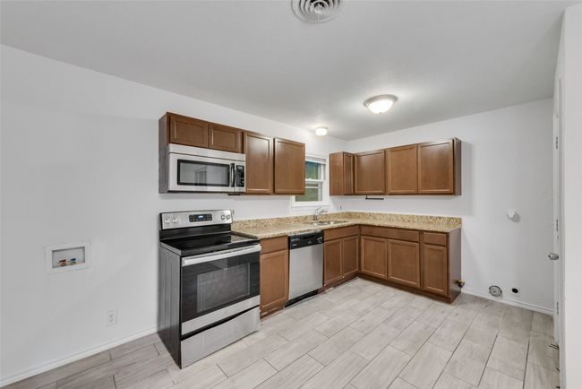 Kitchen featuring a sink, visible vents, brown cabinetry, wood finish floors, and appliances with stainless steel finishes | Image 5